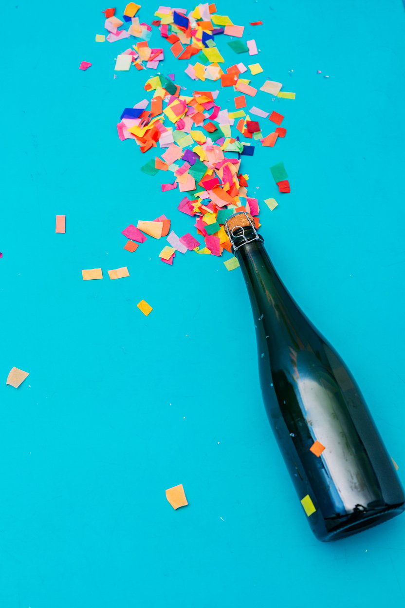 Green Bottle on Blue Background with Confetti Flatlay